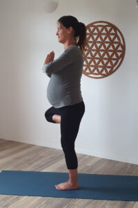 Schwangere Frau übt Yoga im Stehen